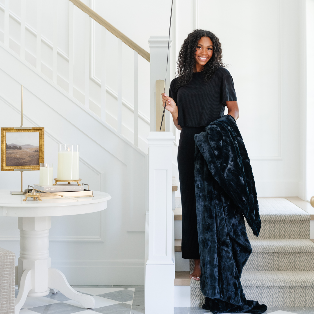 Woman holding a blue velvet garment in a stylish interior setting