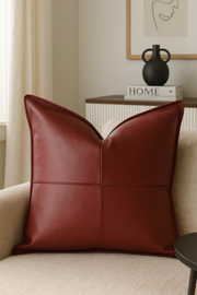 Red leather pillow on a beige sofa with a blurred background