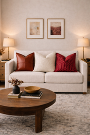 Living room with a beige sofa, red and brown pillows, and a wooden coffee table.
