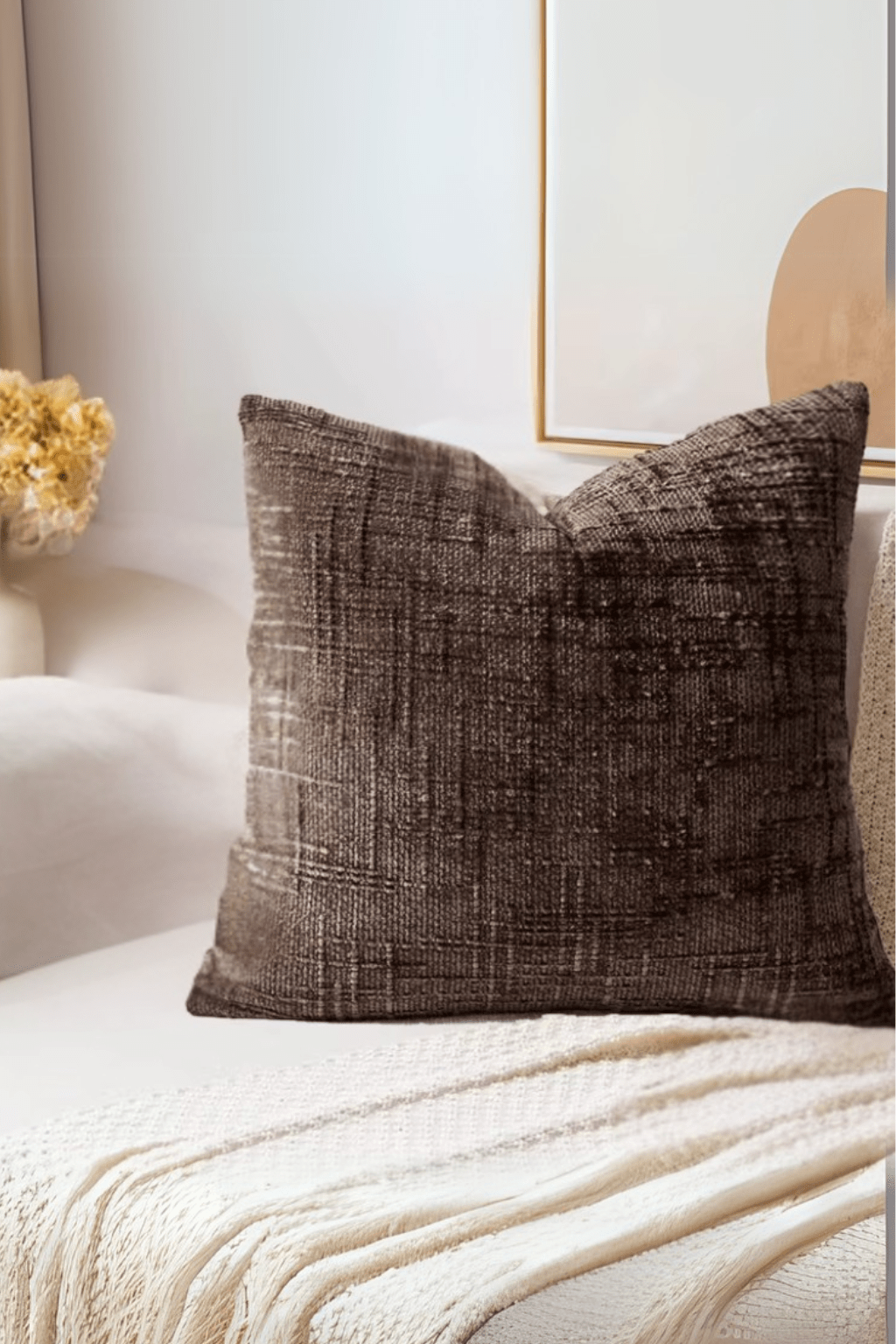 Textured brown pillow on a white sofa with a neutral background