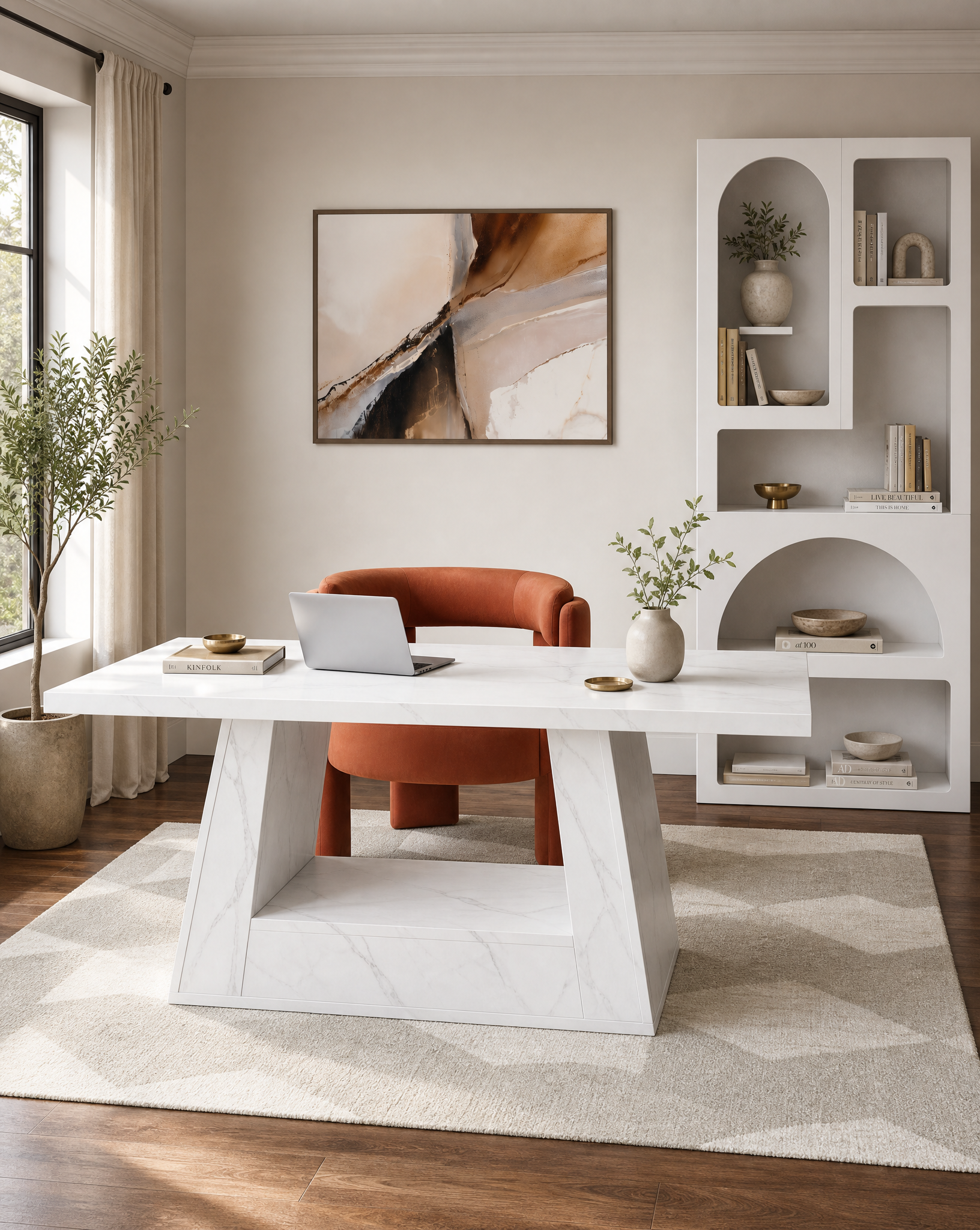 A modern home office scene featuring a white marble-top desk with a sculptural base, paired with an orange-brown leather armchair. The setup is styled on a light beige geometric rug over dark wood floors, with a white built-in shelving unit and a framed abstract painting on the wall.
