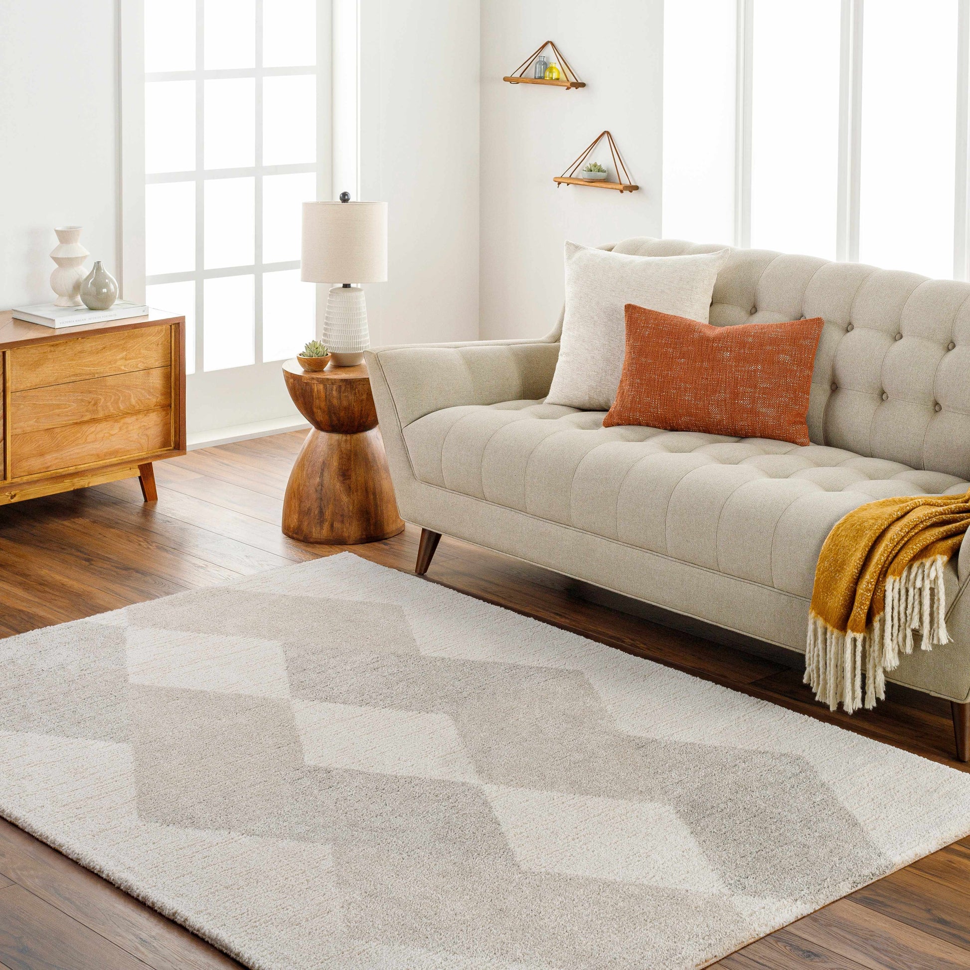 Living room with a beige sofa, geometric rug, and wooden furniture.