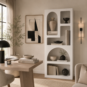 Modern living room with a white bookshelf, wooden desk, and decorative items.