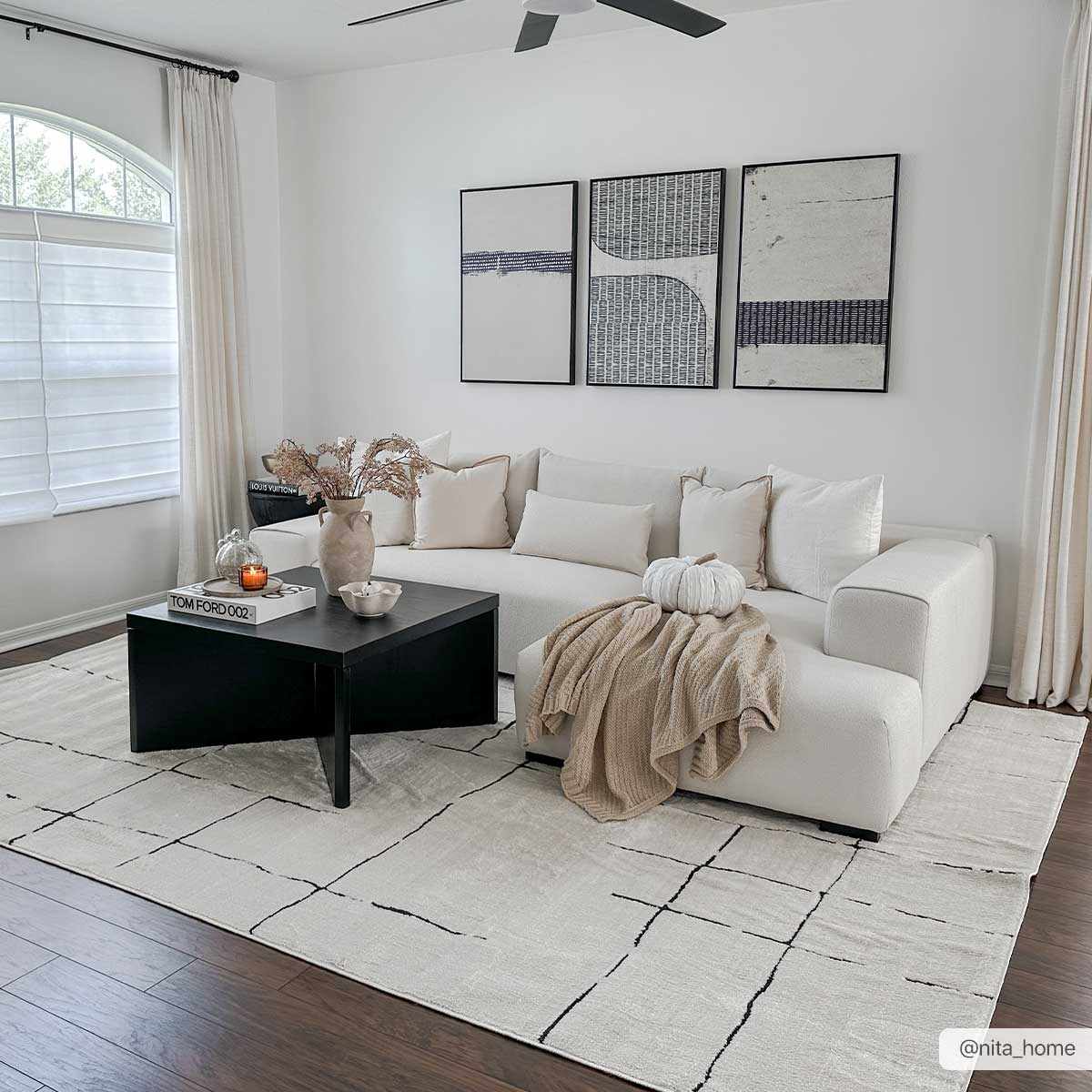 Modern living room with a white sectional sofa, black coffee table, and abstract art on the wall.