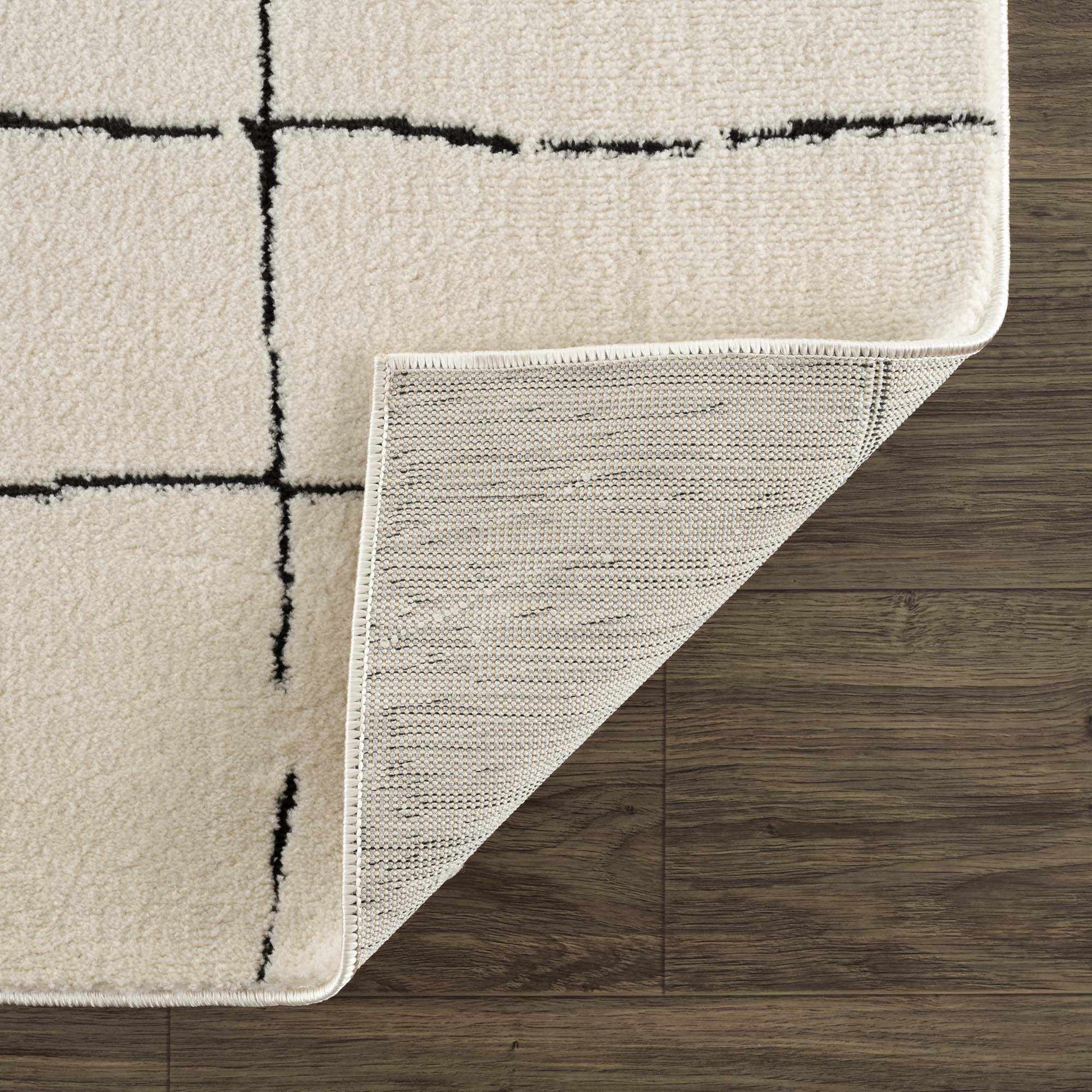 Beige rug with black grid pattern on a wooden floor
