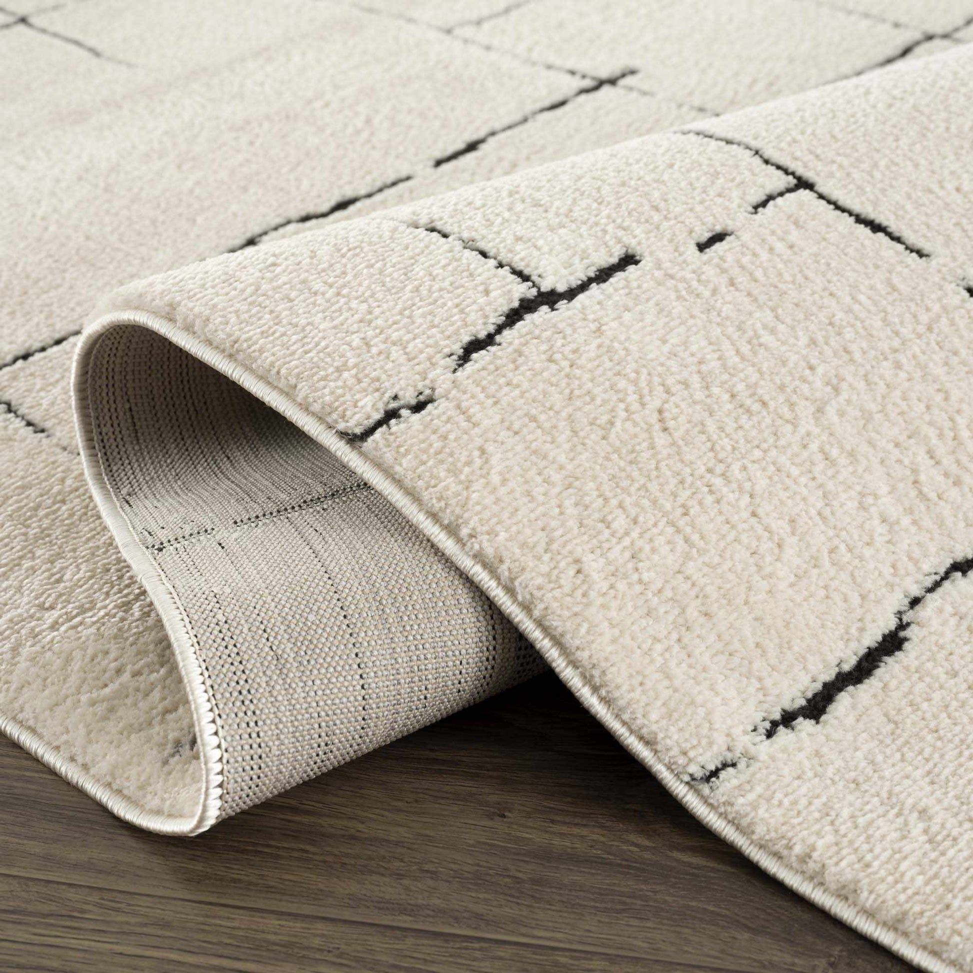 Textured beige rug with geometric pattern on a wooden floor