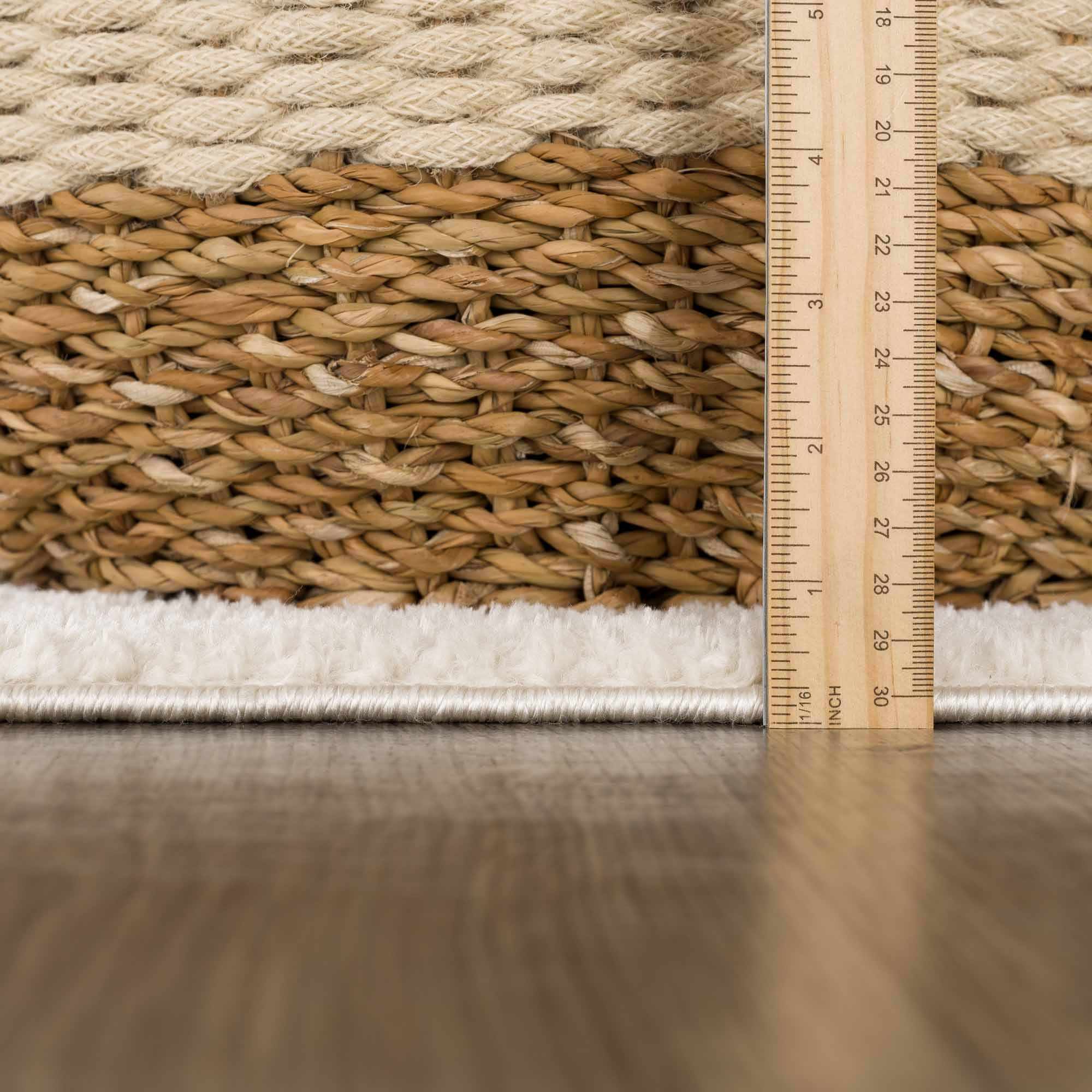 Rug with natural fiber texture and a wooden ruler for scale on a wooden floor.