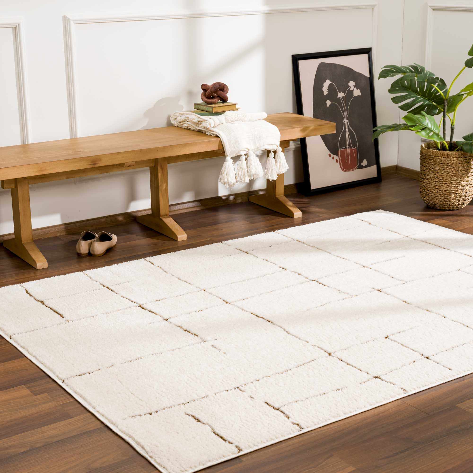 White rug on a wooden floor with a wooden bench and decorative items in the background.