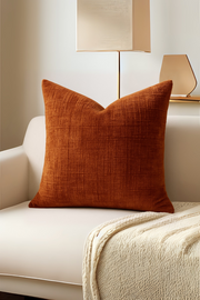 Orange pillow on a white sofa with a lamp in the background