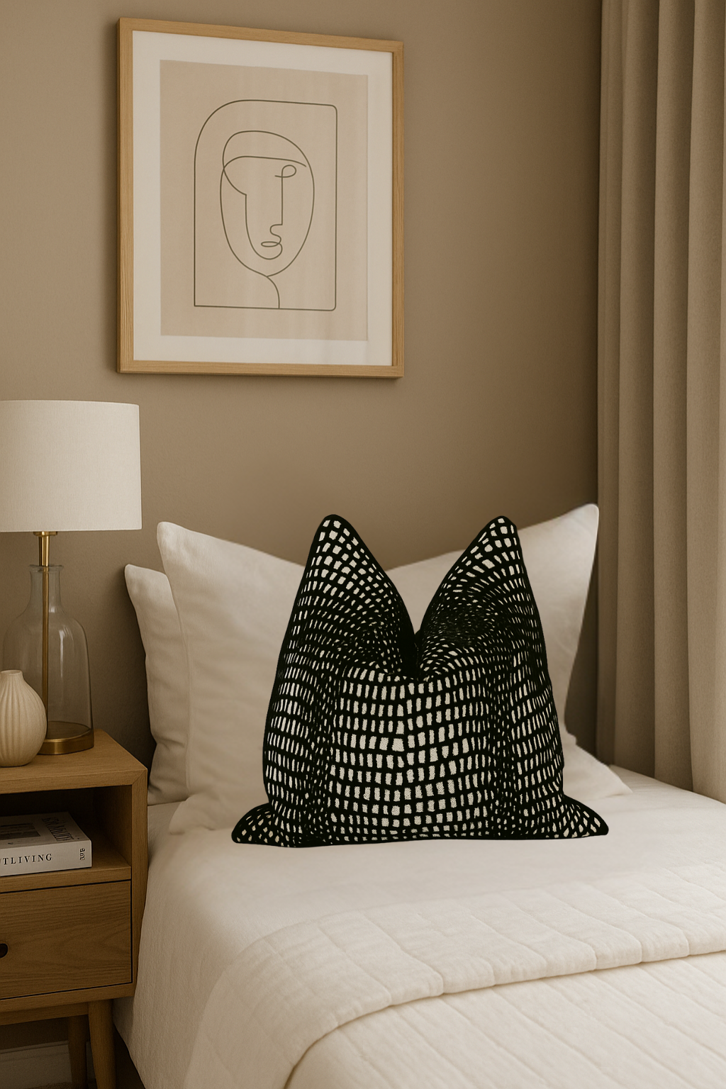 Black textured pillow on a bed with a framed abstract art piece on the wall.
